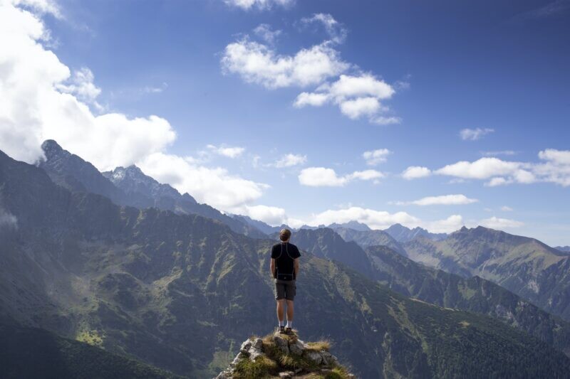 崖の先に立って、雄大な景色を眺める男性